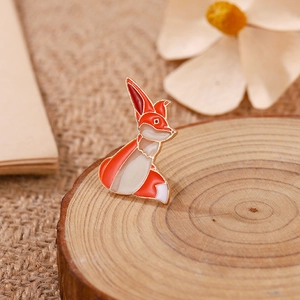 Détail d'une mignonne broche renard en émail avec bord doré sur bois rustique