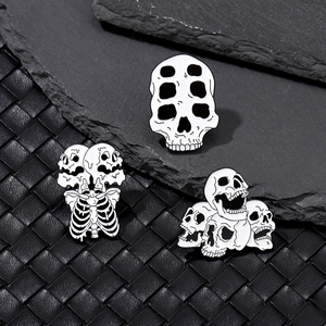 Détails de trois broches gothiques en émail blanc avec crânes et côtes sur cuir noir élégant