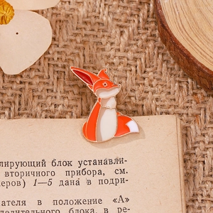 Détails d'un pin's en émail renard orange mignon sur des pages de livre vintage