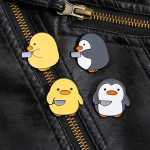 Détail des broches en émail pingouin et canard sur le col d'une veste en cuir noir