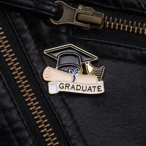 Détail d'un pin's en émail de graduation avec toque et bannière graduate sur cuir