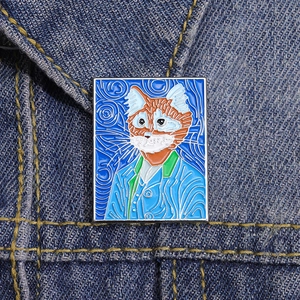 Detailed macro view of Van Gogh style orange cat enamel pin on denim jacket fabric