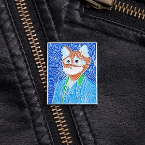 Detail of artistic cat enamel pin inspired by Van Gogh on a black leather jacket