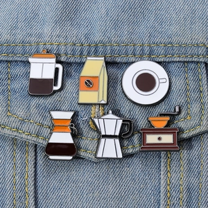 Detail of coffee theme enamel pins including mocha pot and grinder on denim jacket