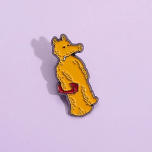 Close-up of a creative cartoon animal enamel pin with vibrant yellow and red colors