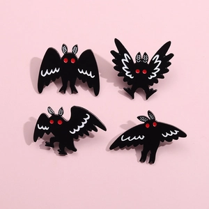 Set of four moth enamel pins with red eyes on a pink background, macro detail view