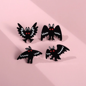 Detailed view of four black enamel pins featuring gothic bat and moth designs