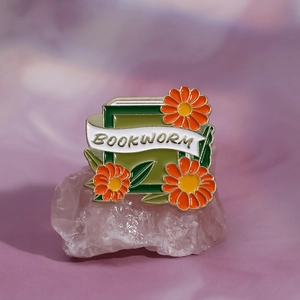 Détail de la broche émaillée Bookworm avec fleurs orange sur cristal rose
