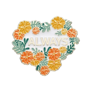 Détail de la broche en émail floral avec fleurs orange et jaunes et texte ALWAYS