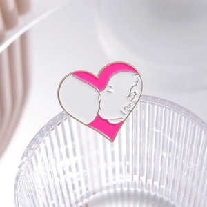 Detailed close-up of a pink heart enamel brooch featuring a mother and child design
