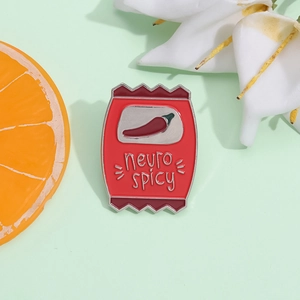 Macro d'un pin's en émail en forme de sachet de piment avec texte neuro spicy humoristique