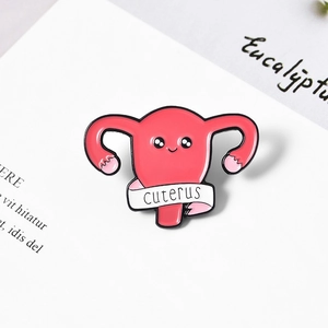 Cute pink uterus enamel pin for doctors and nurses on a minimalist book background