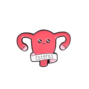 Macro detail of a pink enamel uterus brooch with a white ribbon and cute facial expression