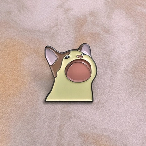 Détail du pin's émaillé Pop Cat avec le design emblématique du mème sur une surface en pierre