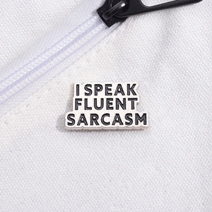Detailed close-up of alloy enamel pin with I Speak Fluent Sarcasm text on white canvas