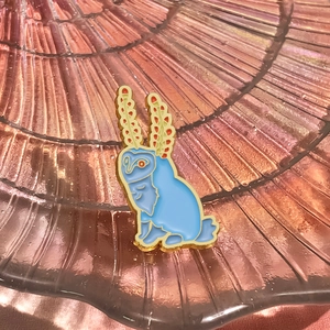 Close-up of blue enamel fox squirrel brooch with gold plating and red ear details
