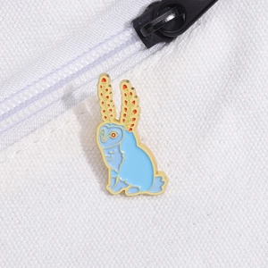 Close-up of blue enamel owl pin with gold trim pinned on a white canvas bag