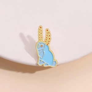 Detail of creative blue owl enamel brooch with orange-tipped ears and smooth glossy finish