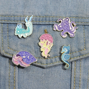 Pastel marine enamel pins with stars and moons on blue denim background fabric