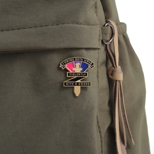 Detail einer Emaille-Schwertnadel mit bisexuellen Farben an einer grünen Stofftasche