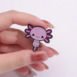 Cute pink axolotl enamel pin held by fingers for backpack and clothing decoration
