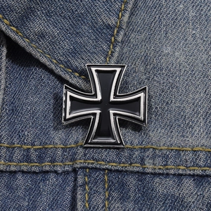 Classic black iron cross metal brooch with silver edges on blue denim jacket