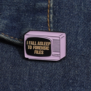 Detailed view of a purple retro TV enamel pin on denim fabric with Forensic Files text