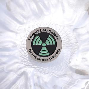 Cartoon enamel pin with glitter radioactive symbol and Forget Lab Safety text