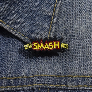 Detailed macro of Super Smash Bros metal enamel pin on blue denim fabric