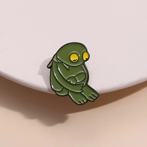 Vue détaillée de la broche grenouille en émail vert foncé avec de grands yeux jaunes