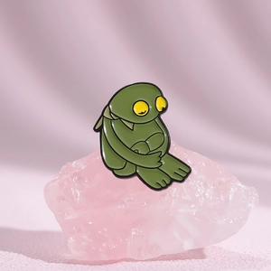 Détail d'un pin's émaillé vert Kermit la grenouille sur une pierre de cristal rose