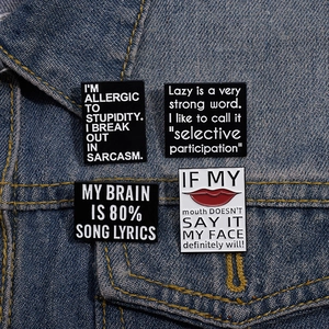 Set of four creative enamel pins with humorous quotes pinned on a denim jacket pocket
