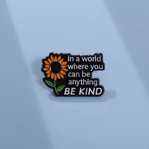 Detailed view of sunflower enamel pin with 'BE KIND' inspirational quote on blue background