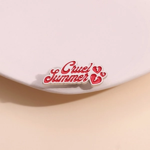 Détail de la broche émaillée Cruel Summer avec motifs de cœur rouge et bords argentés