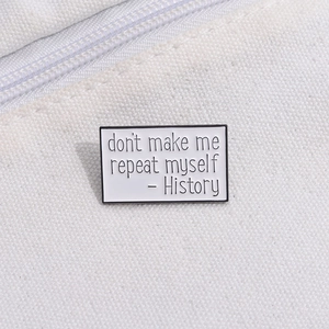 Detail of a rectangular white enamel pin with black text: Don't make me repeat myself - History