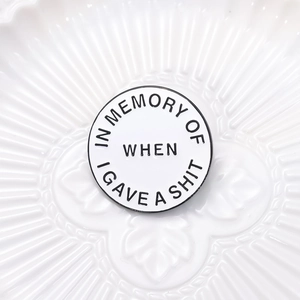 Detail view of round enamel pin with ironic text on a decorative white porcelain plate