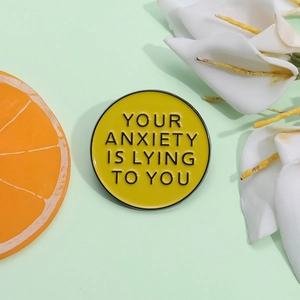 Détail du pin's en émail jaune avec l'inscription Your Anxiety Is Lying To You