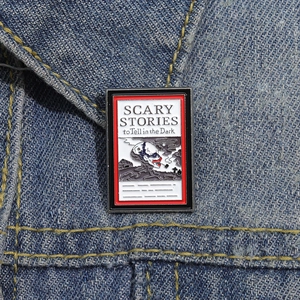 Scary Stories to Tell in the Dark enamel pin on blue denim fabric background