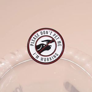 Detail showing the polished enamel texture and warning text on the round service dog pin