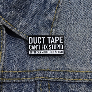 Lustige Duct Tape Can't Fix Stupid Emaille-Anstecknadel an einer Jeansjacke