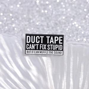 Lustige schwarze Emaille-Brosche mit Spruch Duct Tape Can't Fix Stupid auf weißem Tablett