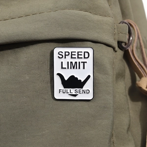 Detail shot of SPEED LIMIT enamel pin with Shaka hand icon on olive canvas background