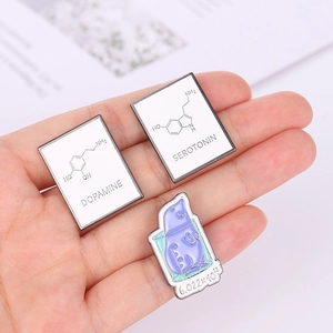 Detailed shot of science enamel pins featuring Dopamine Serotonin formulas and lab beaker