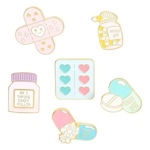 Macro detail of six enamel medical pins featuring pill bottles and creative hearts