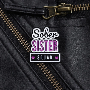 Detail der Sober Sister Squad Emaille-Anstecknadel auf schwarzer Lederjacke mit Reißverschluss