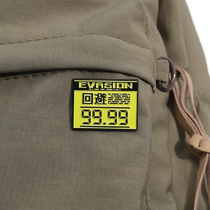 Detail shot of yellow enamel pixel art pin with Evasion text on green canvas bag