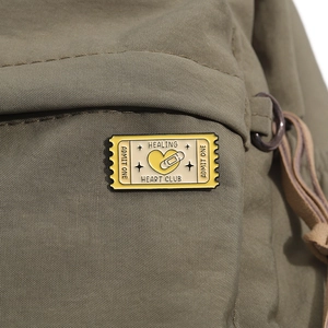 Vue macro du pin's en émail Healing Heart Club sur un sac à dos en nylon vert