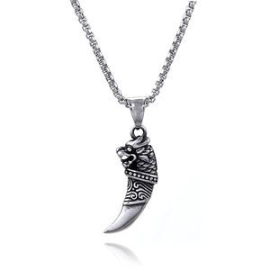 Macro shot of retro tribal tiger tooth pendant with dragon head carvings on box chain