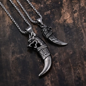 Detailed view of vintage tribal tooth pendants with wolf head carvings on wooden background