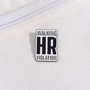 Macro shot of rectangular enamel pin with Walking HR Violation text on canvas